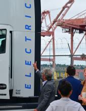an electric truck with port cranes in the backgroup